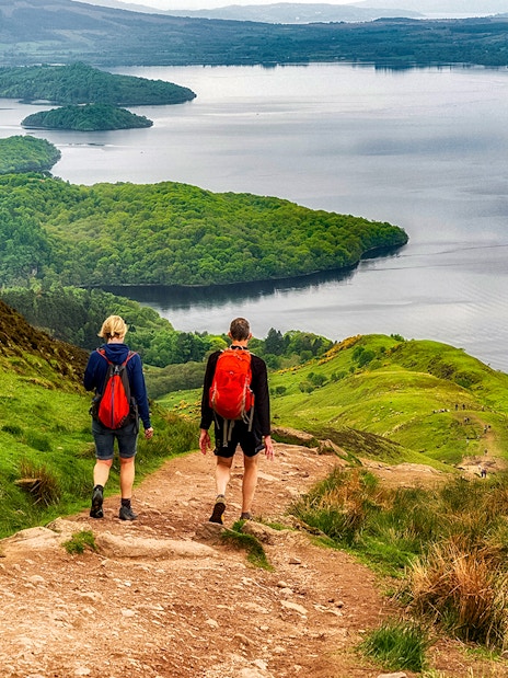 Hikers on a trail overlooking a loch in the Isle of Skye, The Highlands.