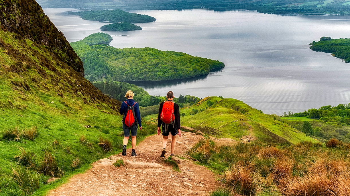 Hikers on a trail overlooking a loch in the Isle of Skye, The Highlands.