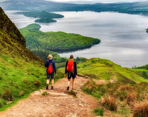 Hikers on a trail overlooking a loch in the Isle of Skye, The Highlands.