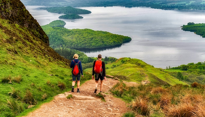 Hikers on a trail overlooking a loch in the Isle of Skye, The Highlands.