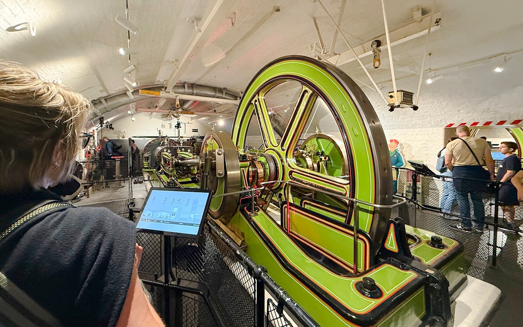 Tower Bridge engine room with green machinery and visitors exploring.