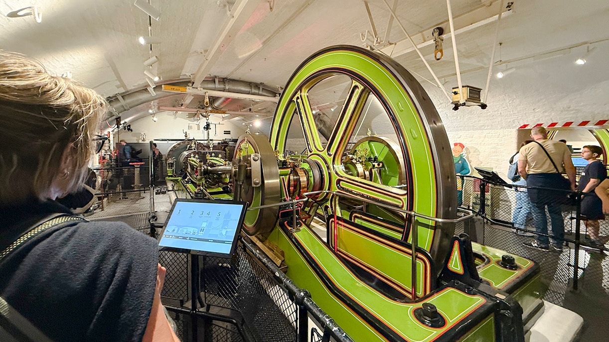 Tower Bridge engine room with green machinery and visitors exploring.