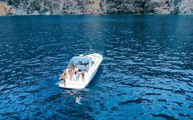 Boat with tourists on dolphin and whale watching tour near Calheta cliffs.