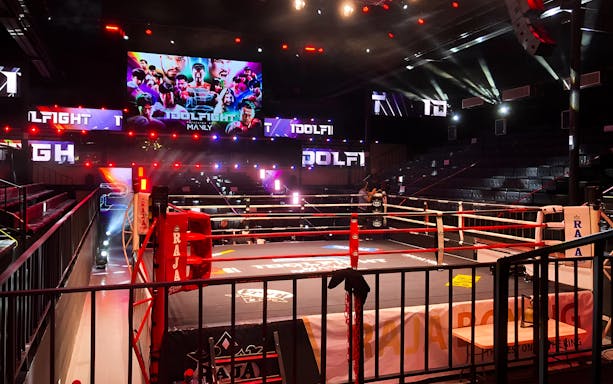 Muay Thai boxing ring at World Siam Stadium, Tawanna Bangkapi, with vibrant lights and empty seats.