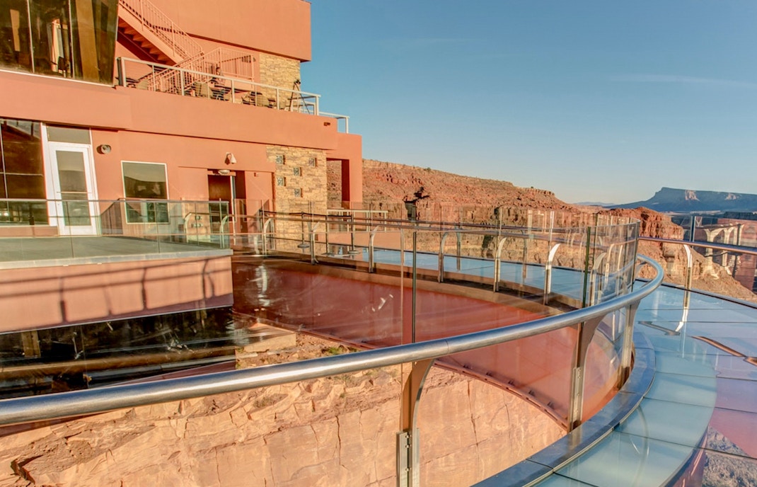 Tourists viewing the Grand Canyon West Rim from an observation point with a clear sky backdrop.