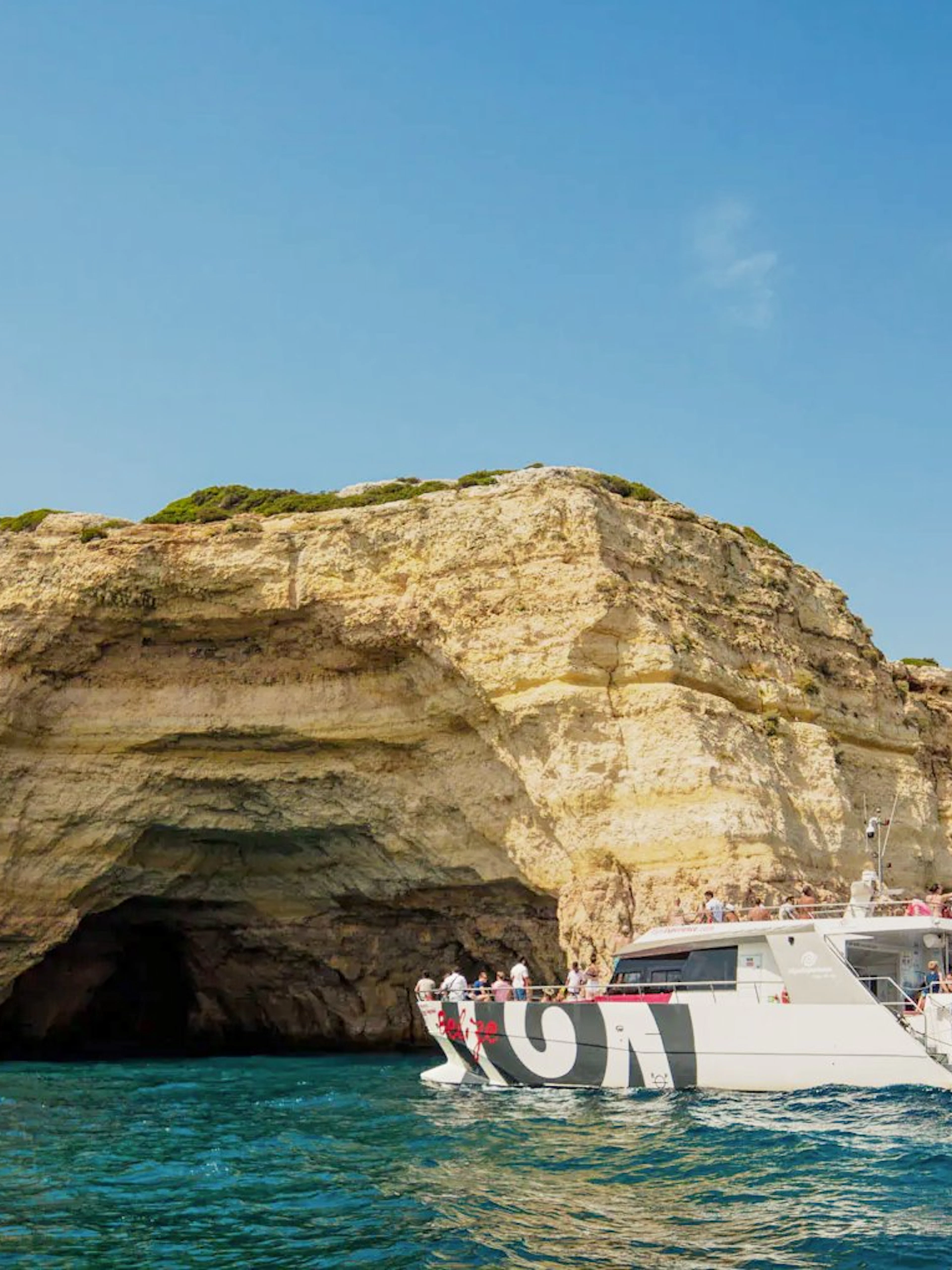 Catamaran with tourists approaching Benagil Caves, Algarve coast, Portugal.