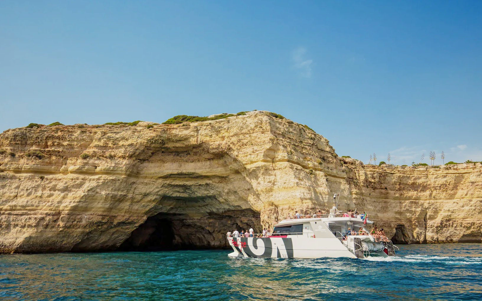 Catamaran with tourists approaching Benagil Caves, Algarve coast, Portugal.
