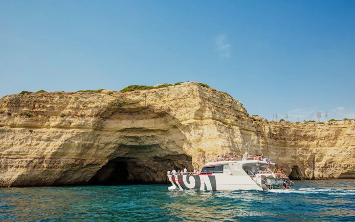 Catamaran with tourists approaching Benagil Caves, Algarve coast, Portugal.