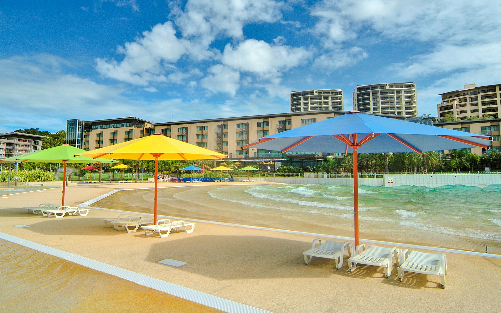 Wave Lagoon in Darwin with colorful umbrellas and lounge chairs by the water.