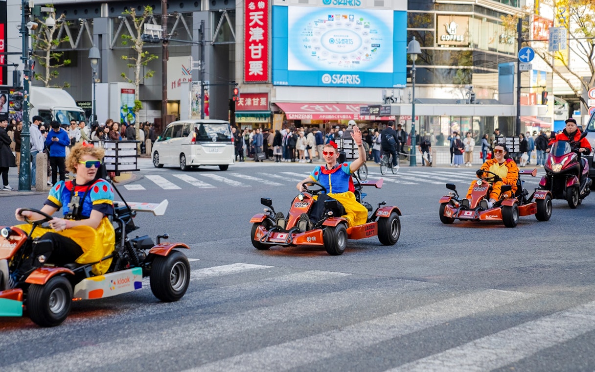 Tourists in costumes go-karting through Shibuya crossing in Tokyo.