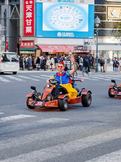 Tourists in costumes go-karting through Shibuya crossing in Tokyo.