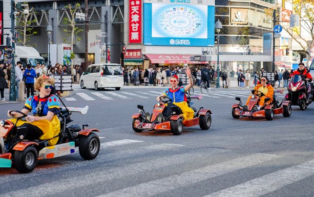 Tourists in costumes go-karting through Shibuya crossing in Tokyo.