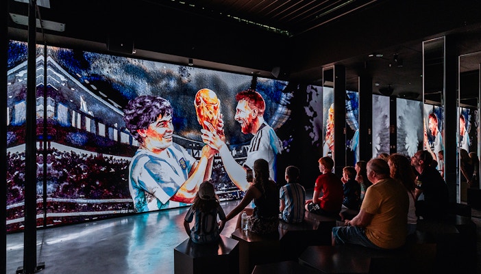 Football fans enjoying the LEGENDS tour, featuring a display of Messi's iconic moments, at the Home of Football museum