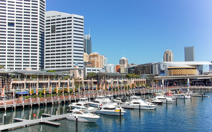 Boats docked at Darling Harbour with city skyline in Sydney.