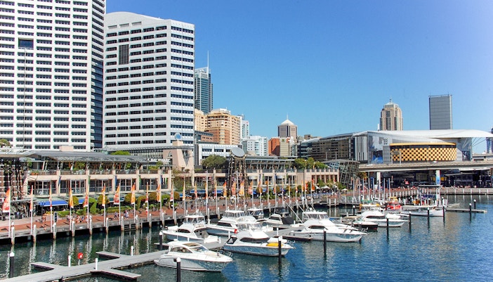 Boats docked at Darling Harbour with city skyline in Sydney.