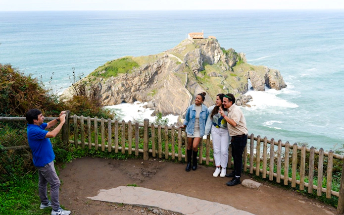 Tourists posing at Dragonstone, Mundaka with ocean view, part of Bilbao to Guernica tour.