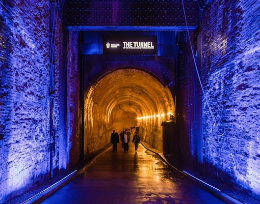 Tourists walking into the illuminated Tailrace Tunnel at Niagara Parks Power Station.