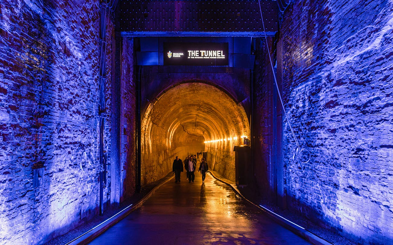 Tourists walking into the illuminated Tailrace Tunnel at Niagara Parks Power Station.