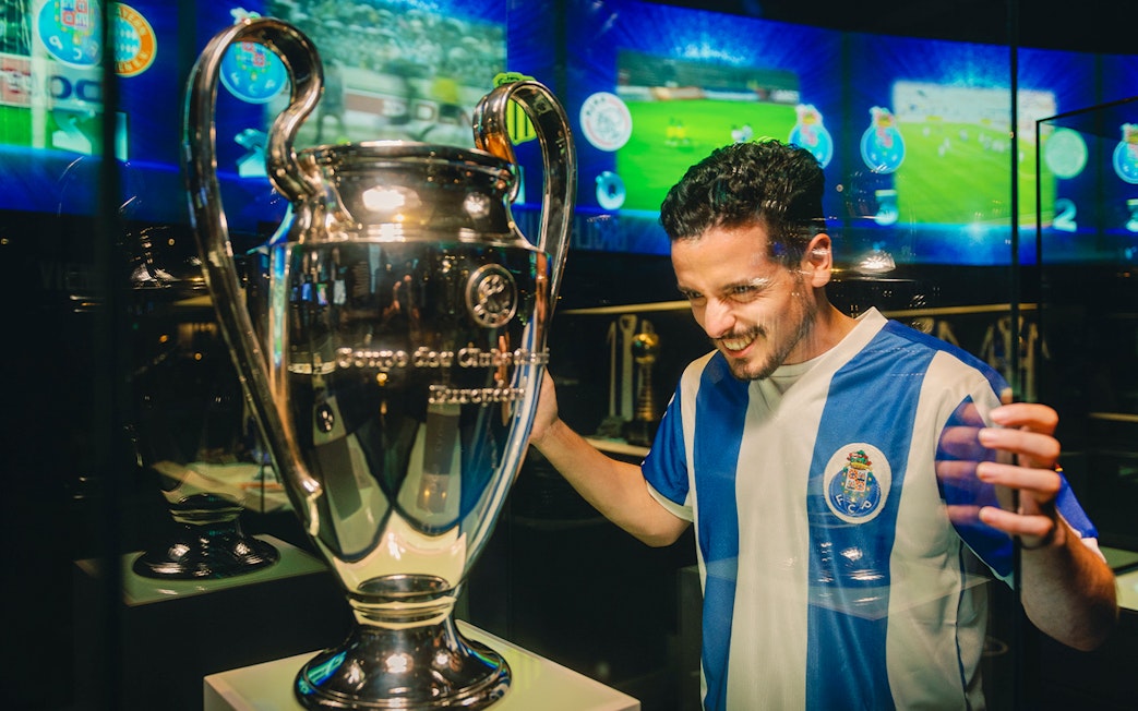 Visitor admiring trophy at FC Porto stadium museum.