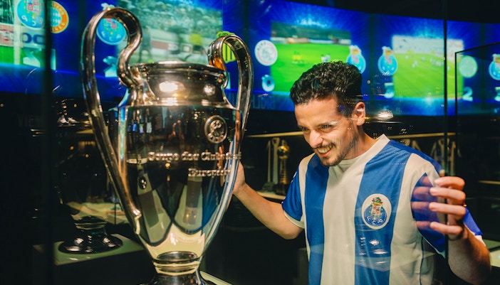 Visitor at FC Porto stadium museum viewing a trophy display.