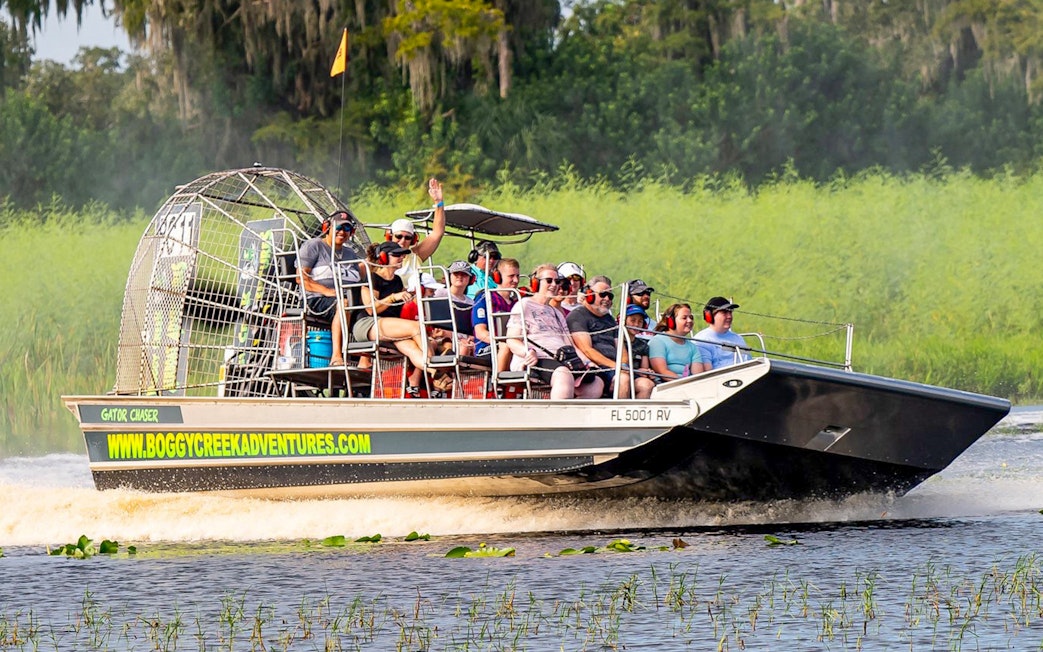Guests on an airboat tour at Boggy Creek, Florida, enjoying the ride through wetlands.