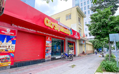 Saigon City Sightseeing tour office with vibrant red signage on a busy street.