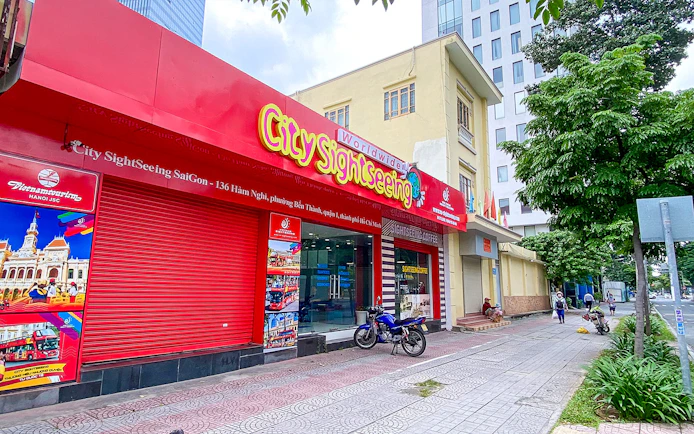 Saigon City Sightseeing tour office with vibrant red signage on a busy street.