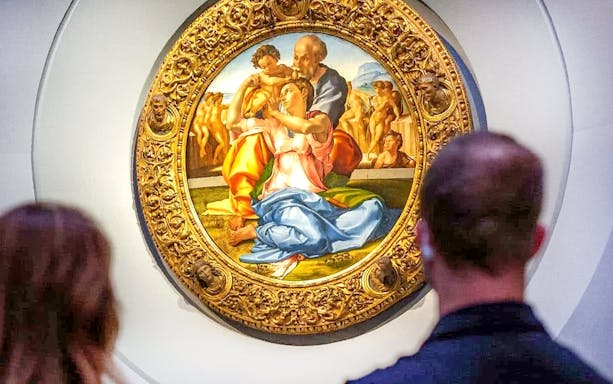 The Holy Family painting by Michelangelo at Uffizi Gallery, viewed by visitors.