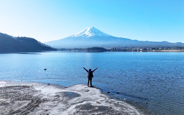 Traveler by Lake Kawaguchi with Mount Fuji in background on Tokyo day trip.