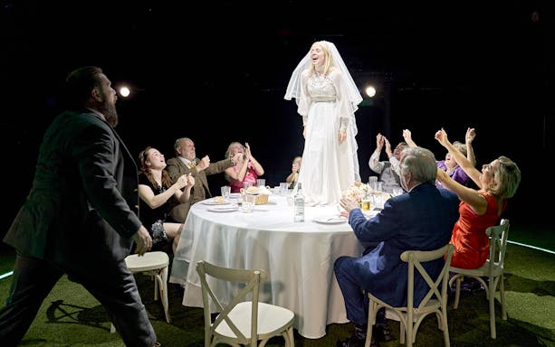 Bride standing on table surrounded by cheering guests at a wedding reception, "Till The Stars Come Down" event.