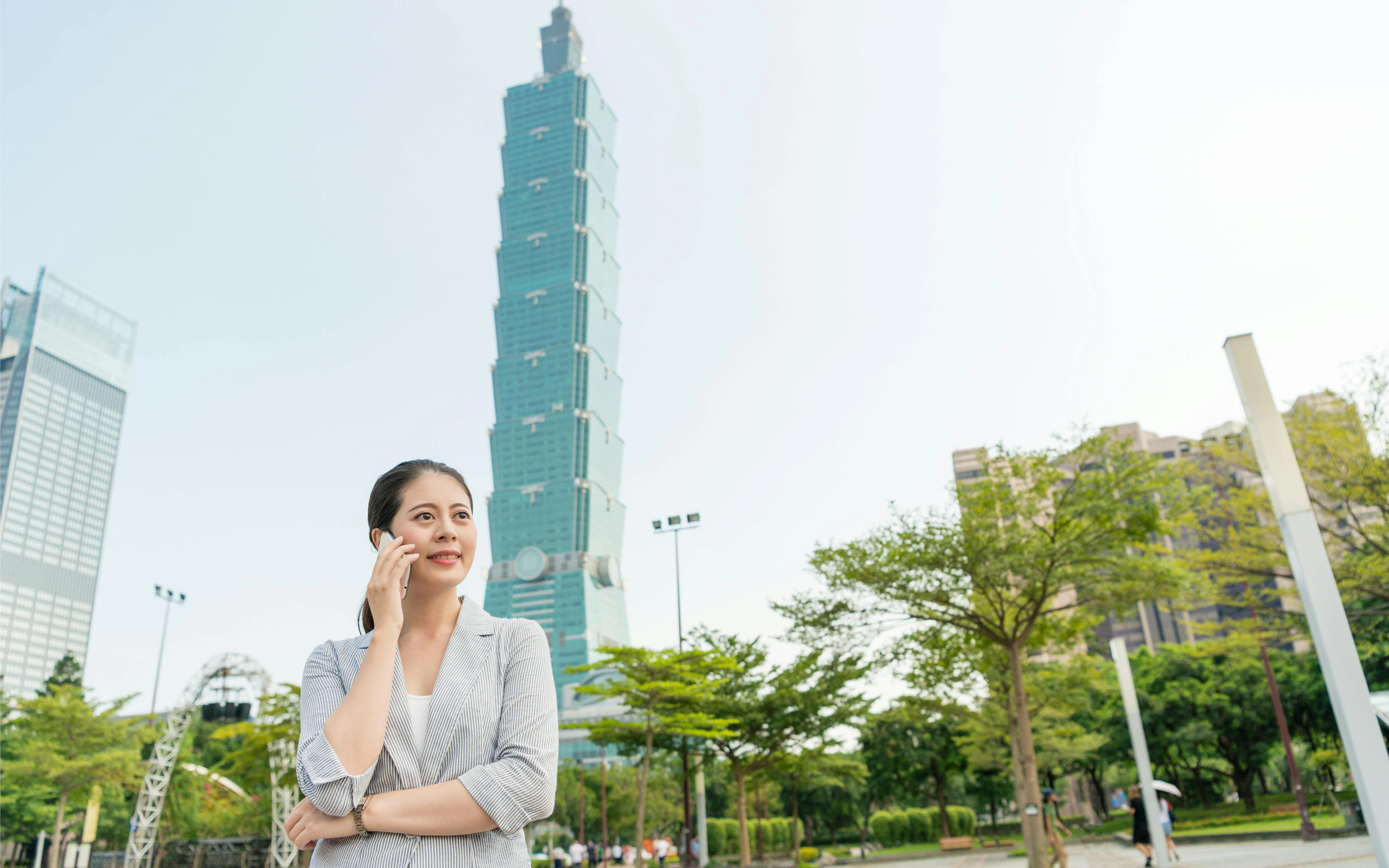 Person on phone near Taipei 101 in Taiwan.