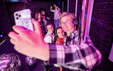 Visitors taking a selfie at The Upside Down Amsterdam with disco balls and headphones.