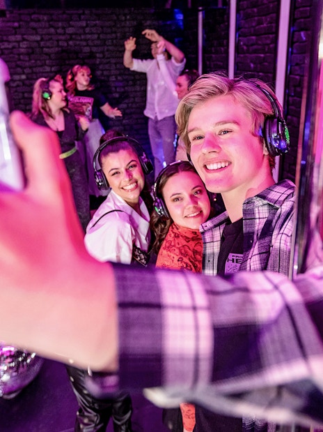 Visitors taking a selfie at The Upside Down Amsterdam with disco balls and headphones.