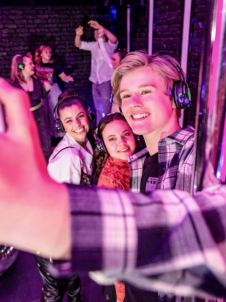 Visitors taking a selfie at The Upside Down Amsterdam with disco balls and headphones.