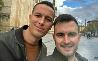 Two people smiling in front of a historic building in Bordeaux, part of a self-guided city exploration game.
