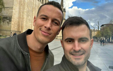 Two people smiling in front of a historic building in Bordeaux, part of a self-guided city exploration game.