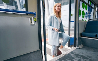 Woman boarding shuttle bus at Brussels South Charleroi Airport with ticket in hand.
