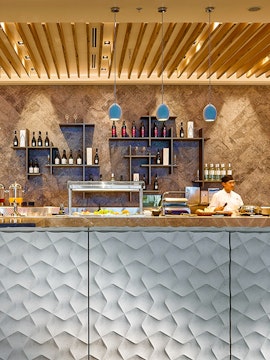 Chef preparing food at Plaza Premium Lounge Brisbane buffet counter.