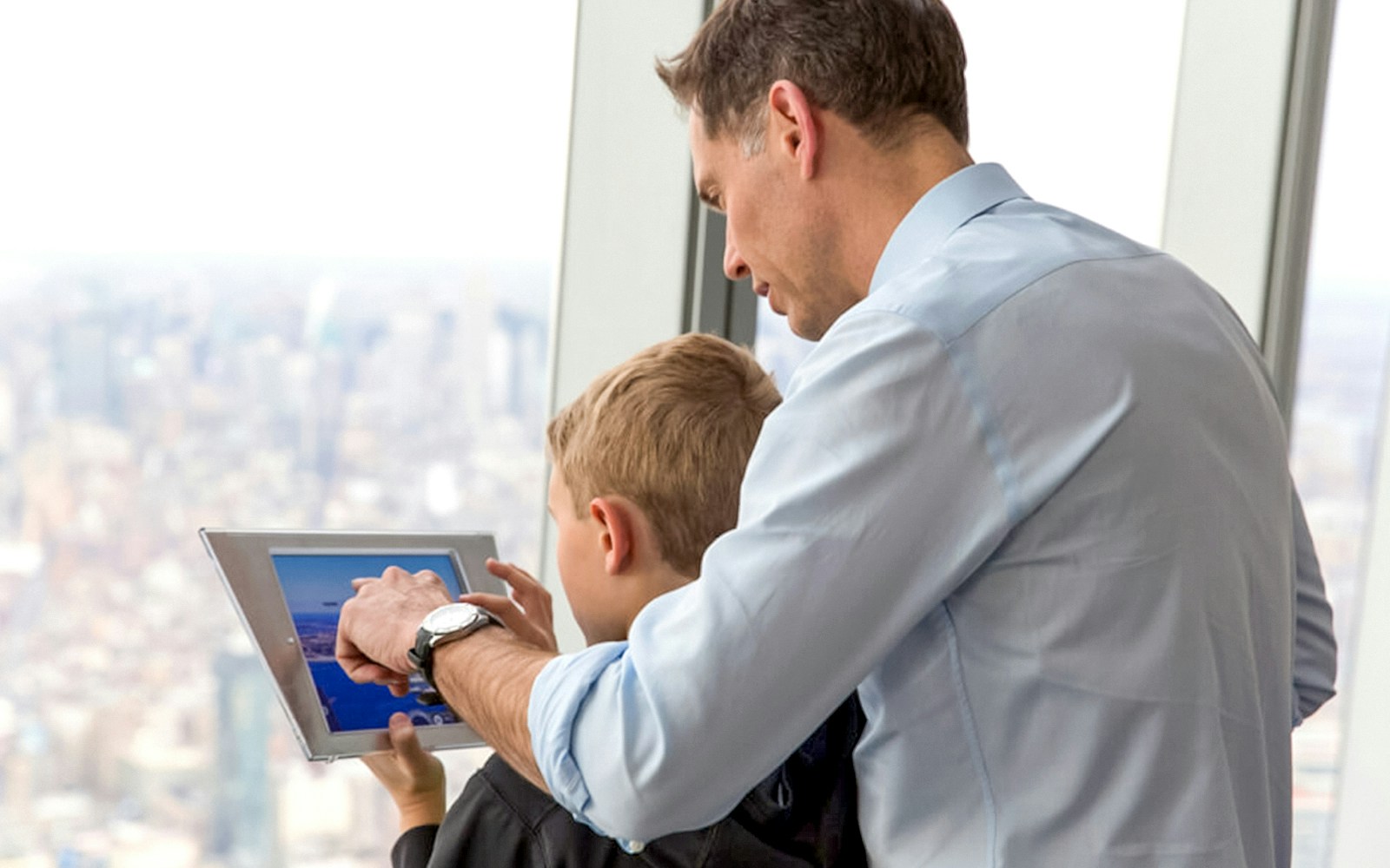 Father and son using a tablet at One World Observatory, New York City.