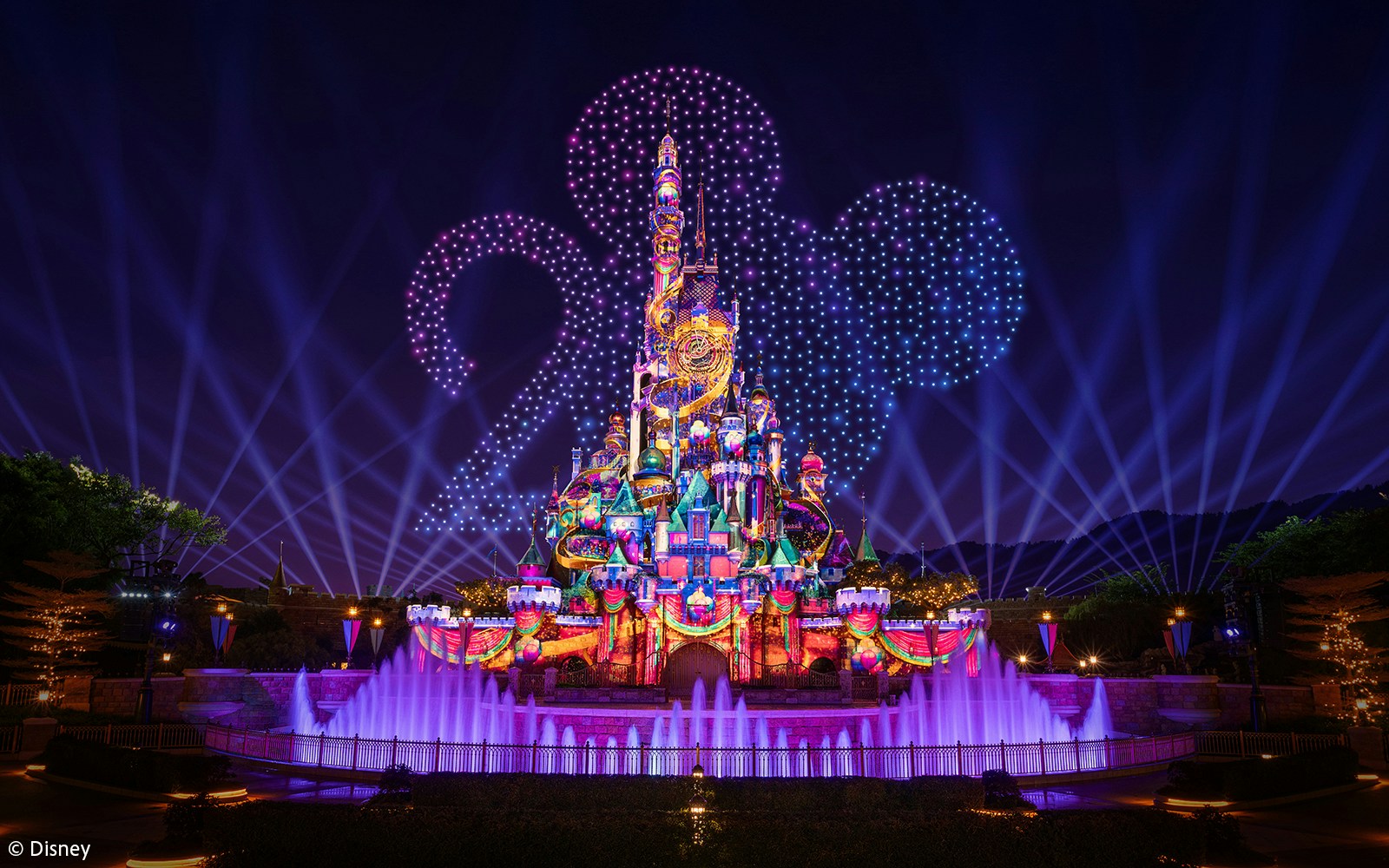 Hong Kong Disneyland castle illuminated for 20th anniversary celebration.