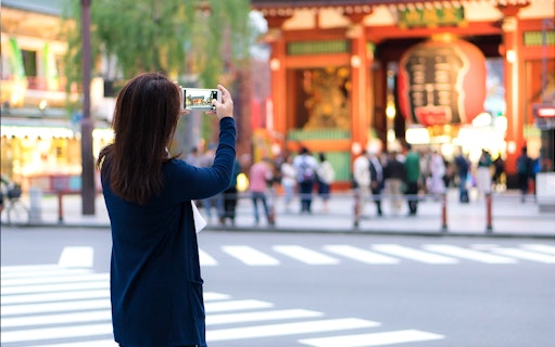 Tourist photographing Senso-ji Temple entrance in Tokyo, Japan.