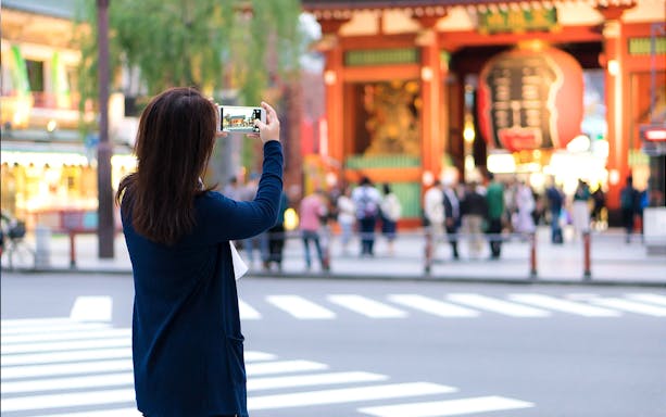 Tourist photographing Senso-ji Temple entrance in Tokyo, Japan.