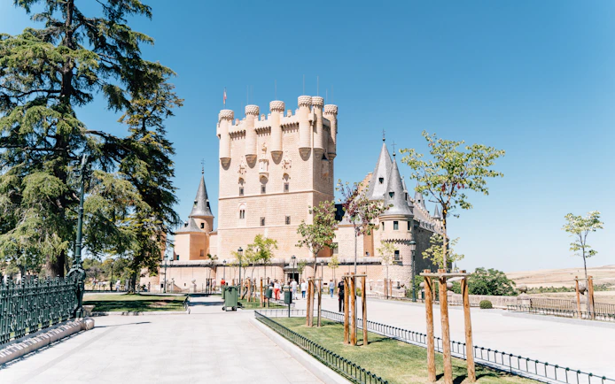 Alcázar of Segovia, a historic castle in Segovia, Spain, with towers and surrounding trees.