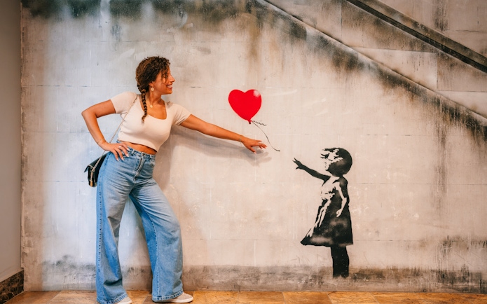 Tourist interacting with Banksy artwork at Banksy Museum Barcelona.