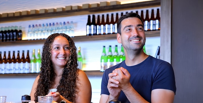 Couple enjoying sushi with sake bottles in the background.