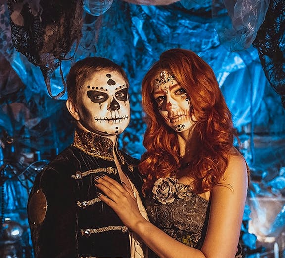 Couple in Halloween costumes with face paint at a themed event in Paris.