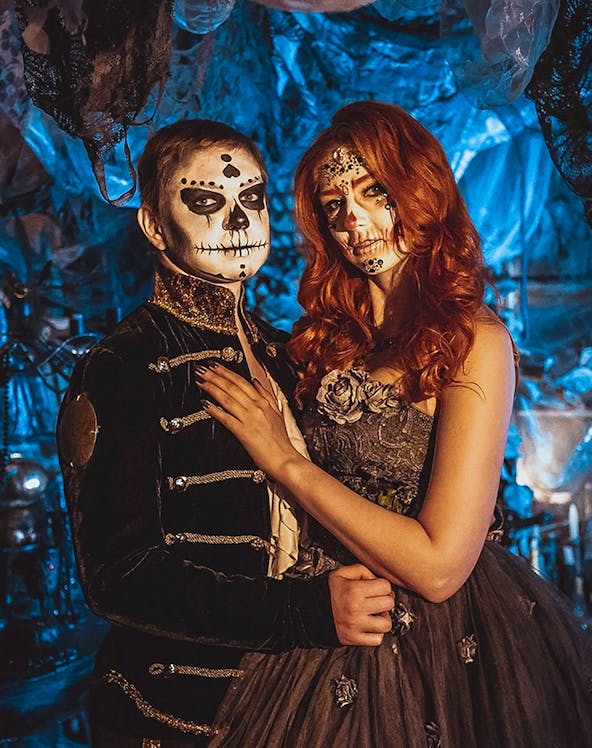 Couple in Halloween costumes with face paint at a themed event in Paris.