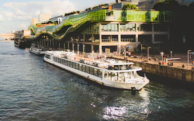 Diamant Bleu cruise ship docked by a modern building in Paris.