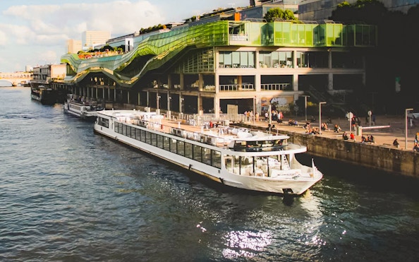 Diamant Bleu cruise ship docked by a modern building in Paris.