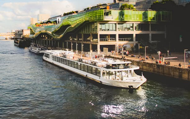 Diamant Bleu cruise ship docked by a modern building in Paris.